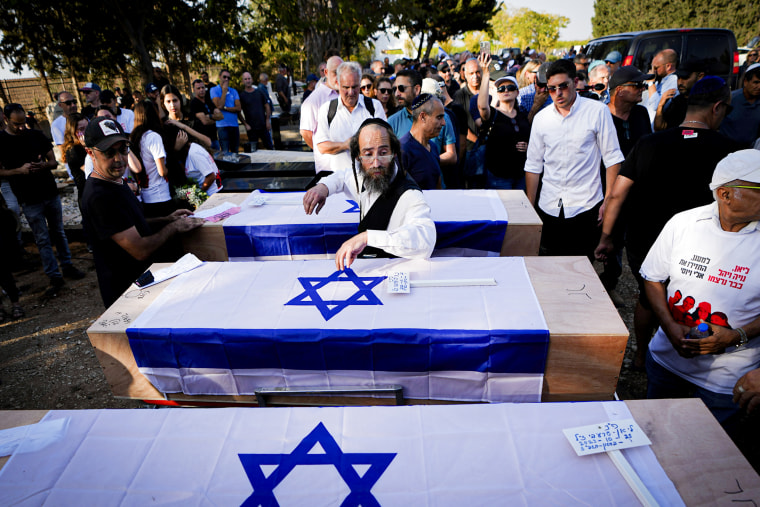 Mourners gather around the coffins at a funeral.