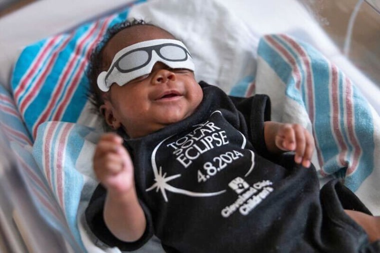 A baby in the Cleveland Clinic Children’s Neonatal Intensive Care Unit wears an eye cover decorated to look like eclipse glasses.