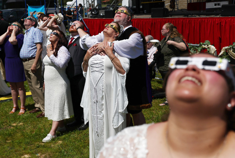 Couples view the solar eclipse during a mass wedding at the Total Eclipse of the Heart festival 