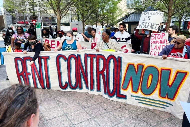 A protest banner reads "Rent Control Now"