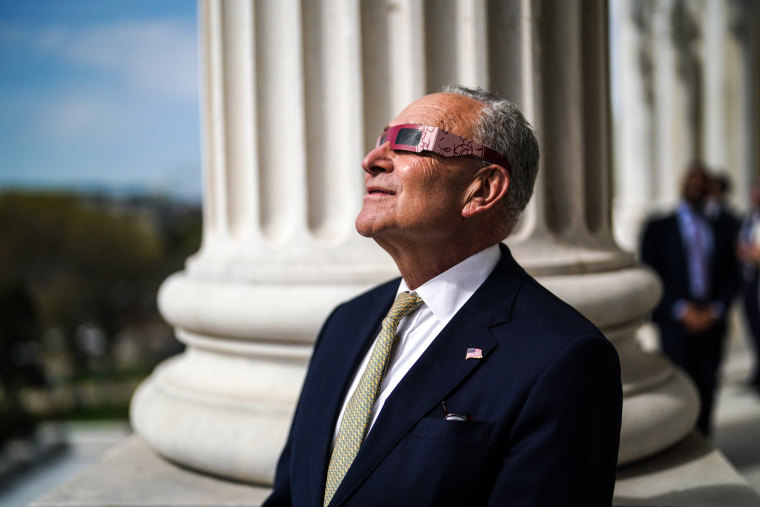 Senate Majority Leader Chuck Schumer observes the eclipse from the balcony of his office in the U.S. Capitol Building.