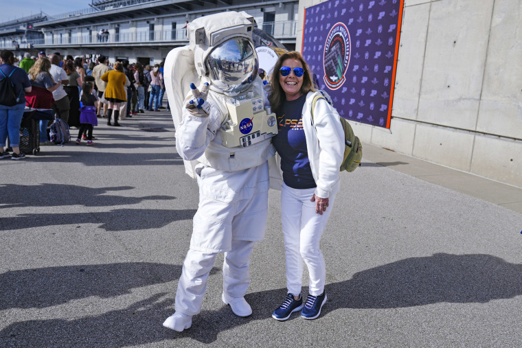 Tamra Sylvester poses with a person dressed as a NASA astronaut during a total eclipse viewing event at the Indianapolis Motor Speedway in Indianapolis, Monday, April 8, 2024.