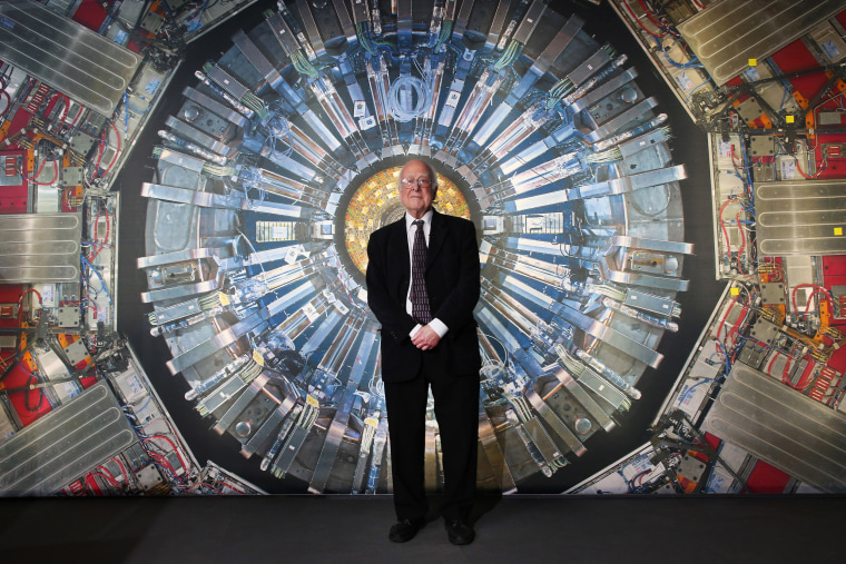 Peter Higgs stands in front of a photograph