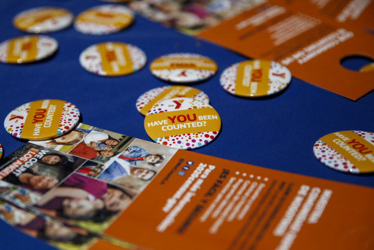 Census 2020 pins and leaflets are displayed on a table during a community food distribution at a YMCA location in Los Angeles