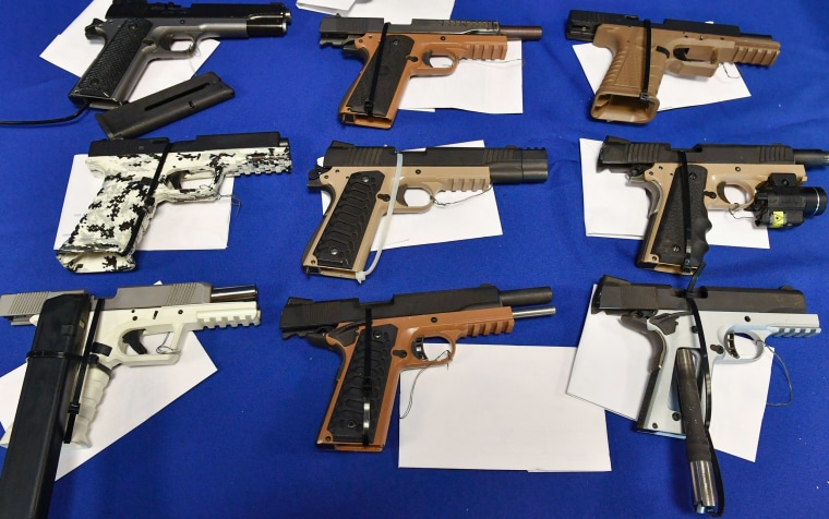 Seized ghost guns are displayed on a table.