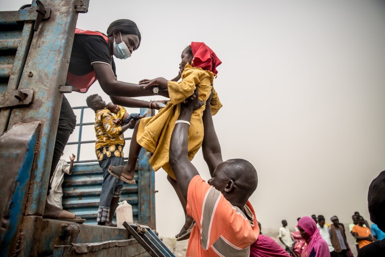 A child is placed in a truck carrying people fleeing the war in Sudan