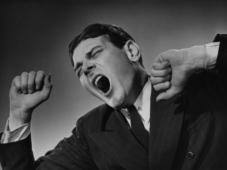 Man in a suit yawns and stretches, circa 1960.