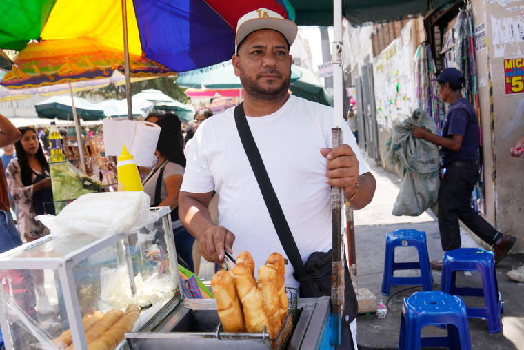 Venezuelan Giovanny Tovar waits for customers at his tequeños or fried breaded cheese sticks' street cart, in Lima