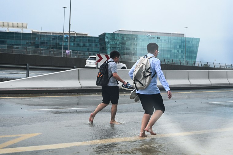 Pedestrians cross a flooded street