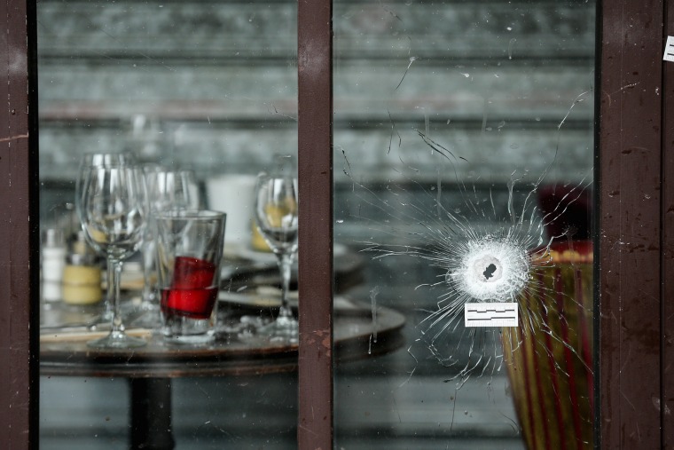A bullet hole through the glass door of a cafe