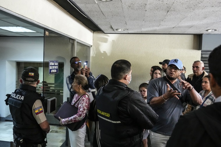 People wait to enter the Venezuelan embassy where Ecuadorian police stand guard in Quito, Ecuador