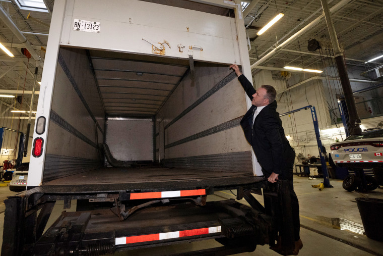 A police officer opens the back of a recovered truck 