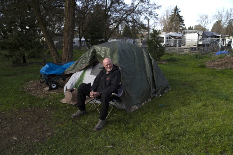 David Wilson sits outside his tent at Riverside Park in Grants Pass, Ore.