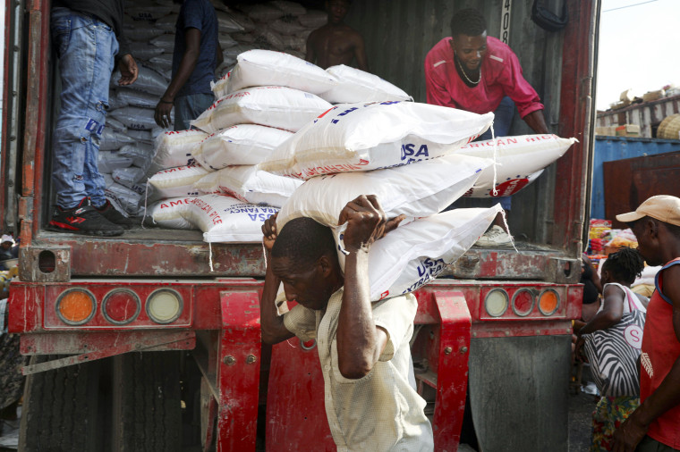 A worker unloads sacks of rice at a market