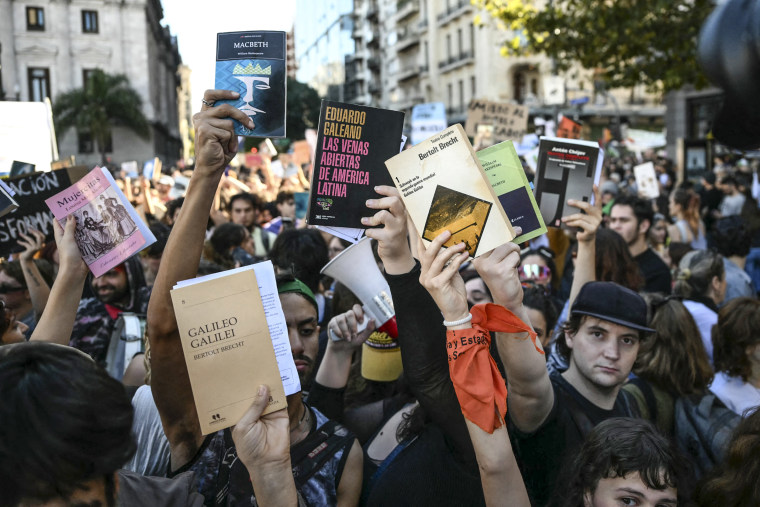Image: Demonstrators raise books during a march in protest of the budget adjustment to public universities 