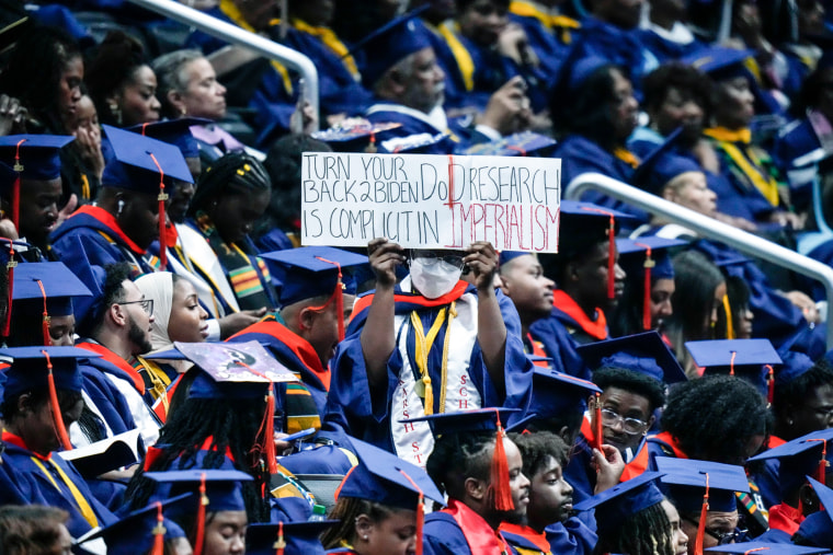 A graduate holds a sign