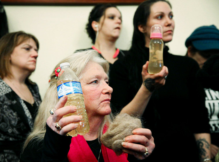 Flint residents hold a bottle full of contaminated water.