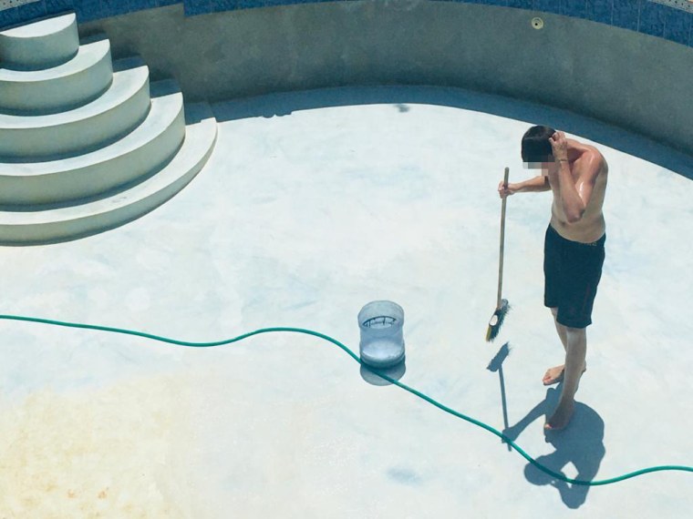 A boy cleans a pool at the Atlantis Leadership Academy. His face has been obscured by NBC News.
