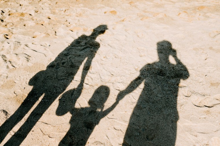 Shadows of parents and their child on a beach