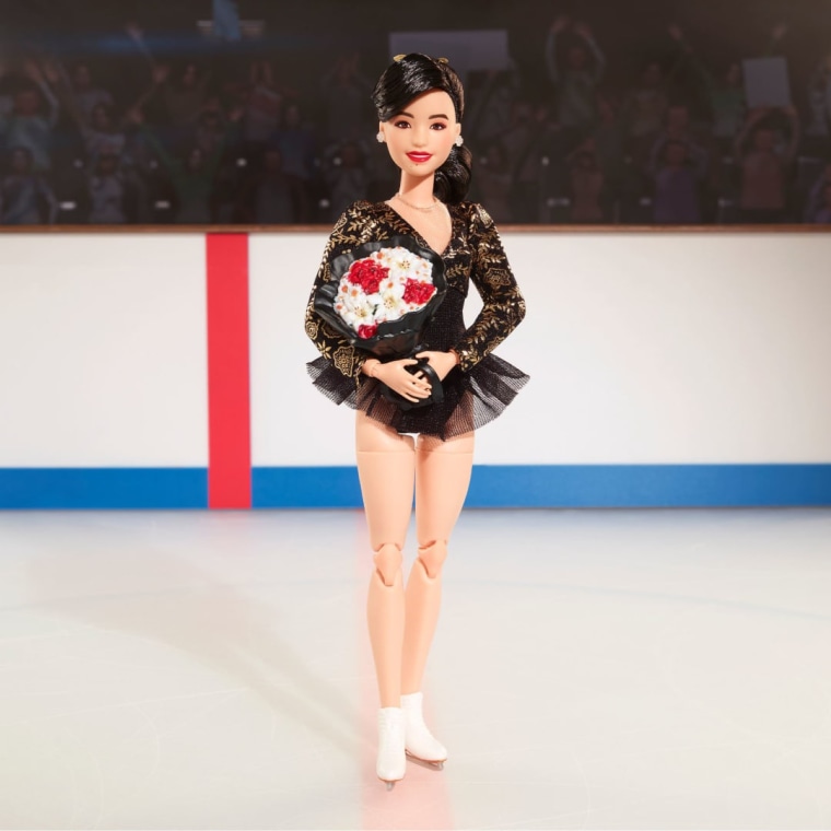 The Barbie doll sparkles in a black leotard with shimmering golden accents in a reproduction of the costume she wore when she won gold at the 1992 Winter Games, designed by Lauren Sheehan.