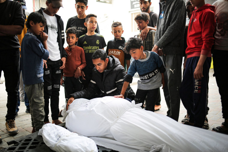 Mourners stand near corpses of an adult and a child killed in overnight Israeli bombardment 