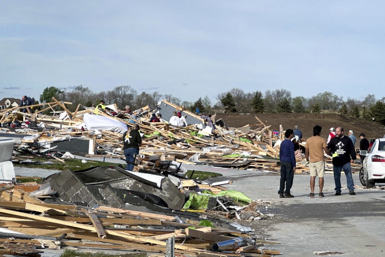 People walk through the rubble of a house that was leveled.