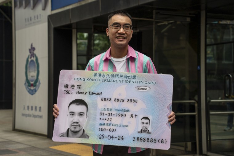 Activist Henry Tse, who won an appeal to change the gender on his ID card, poses with a mock ID card outside the immigration tower after receiving the new document in Hong Kong, Monday, April. 29, 2024.