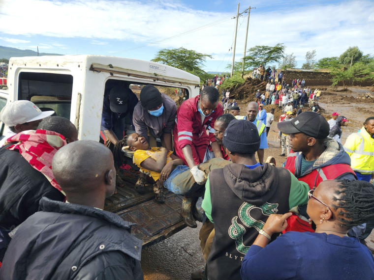 Paramedics carry an injured woman after a dam burst in Kenya.