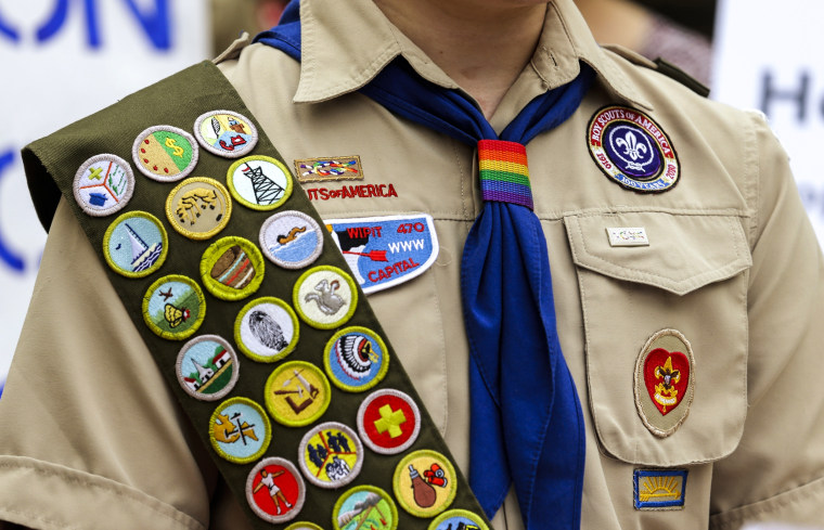 Merit badges and a rainbow-colored neckerchief slider on a Boy Scout uniform.