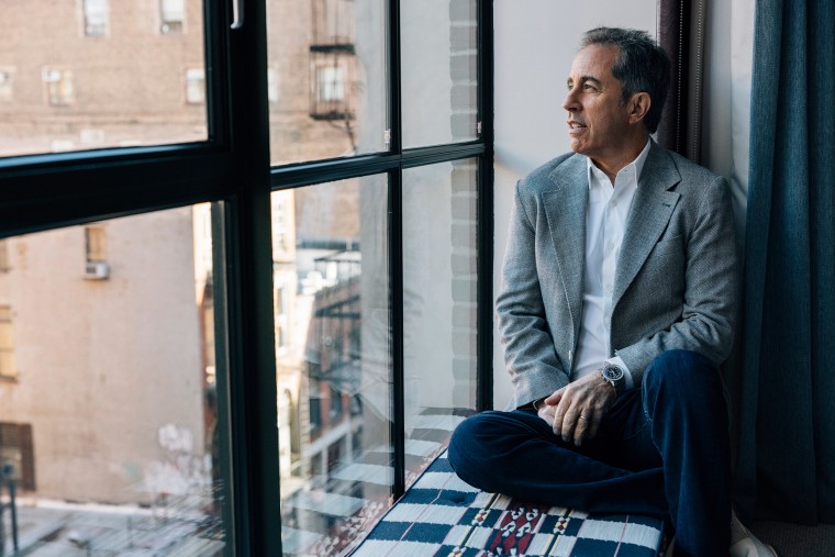 Jerry Seinfeld looks out a window while posing for a portrait