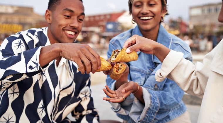 Multiracial friends toasting tacos on promenade