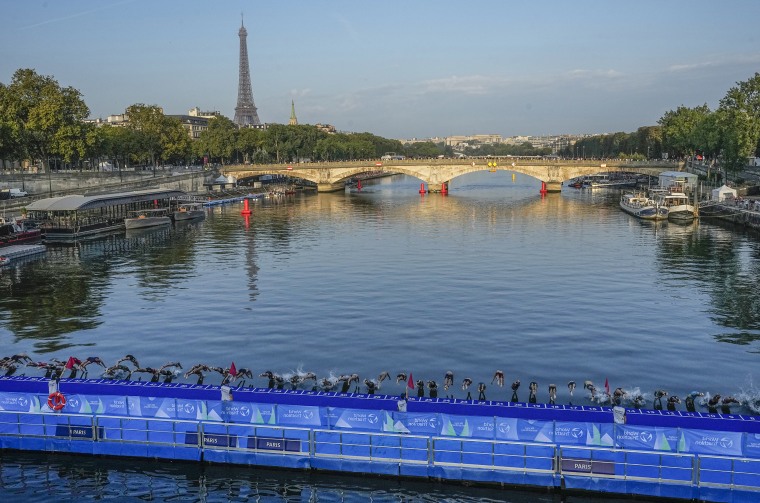 Athletes dive into the Seine river at the start of the women's triathlon test event for the 2024 Olympics Games on Aug. 17, 2023. 