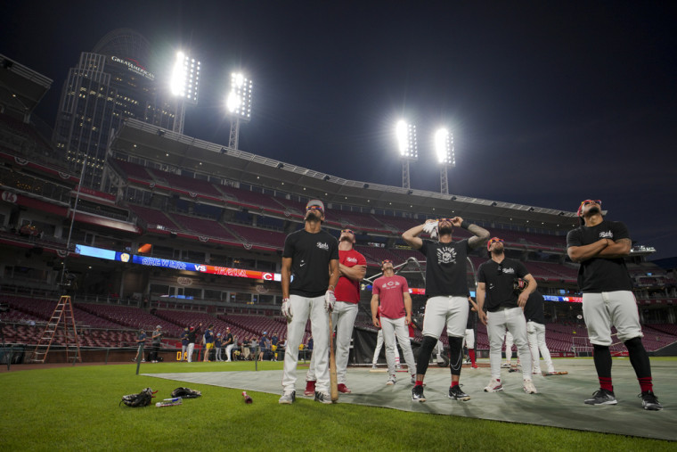El equipo Cincinnati Reds contempla el eclipse antes de un partido de béisbol.
