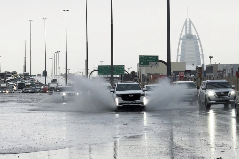 Una camioneta arroja agua a su paso por una carretera anegada, con el edificio Burj Al Arab, de fondo, en Dubai, en los Emiratos Árabes Unidos, el 16 de abril de 2024. 
