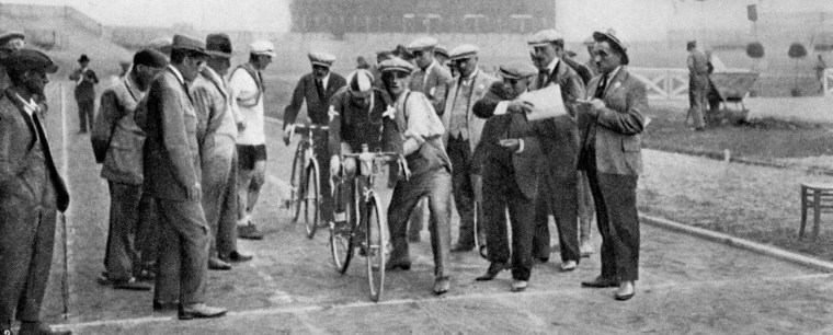Cyclists, surrounded by team members, volunteers and officials, about to set off for the Individual Time Trials during the 1924 Paris Olympics.