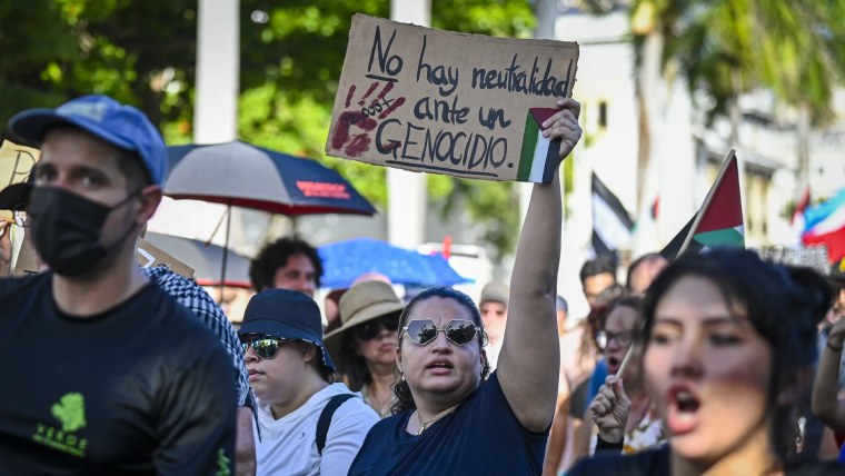 Manifestantes en San Juan, Puerto Rico, marchan en apoyo a palestinos. Al centro, una mujer sostiene un letrero que dice: 