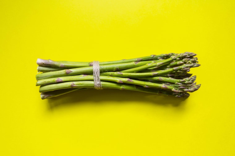 Green asparagus bunch tied with a string on yellow background - Healthy lifestyle and organic food concept