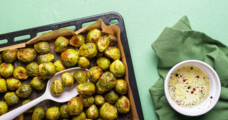 Homemade roasted brussels sprouts in tray on green table.