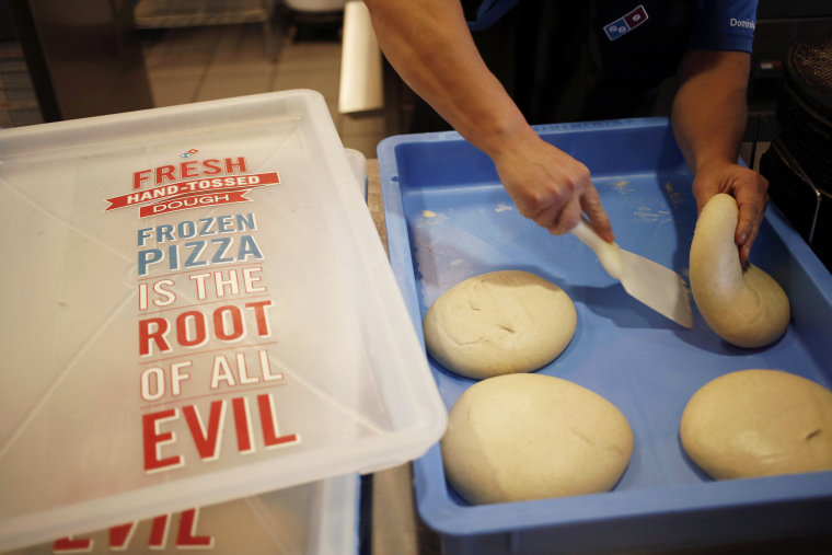 Store supervisor Kim Hopkins grabs a dough ball to make pizza during lunch hour at a Domino's Pizza Inc.