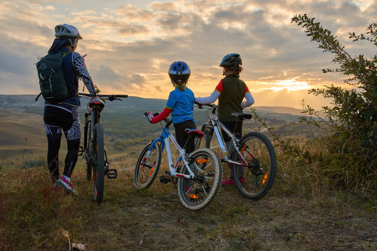 Happy mountain bike family,  outdoors have fun together on a summer afternoon sunset, cycling girls activity
