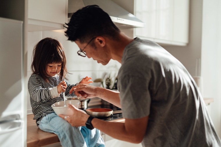 Young Asian father and daughter cooking together in kitchen at home