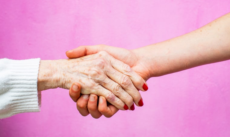Two women's hands, one old and one young.