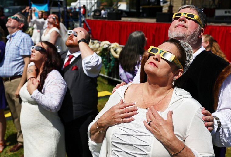 Couples view the solar eclipse during a mass wedding 