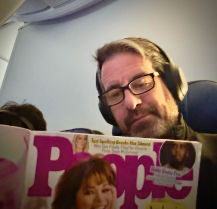 Mike Goodnough reading a People magazine with Valerie Bertinelli on the cover.