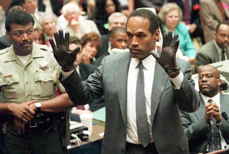 O.J. Simpson shows the jury a new pair of Aris extra-large gloves, similar to the gloves found at the Bundy and Rockingham crime scene 21 June during his double murder trial in Los Angeles. Depety Sheriff Roland Jex(L) and Prosector Christopher Darden(R) look on.   