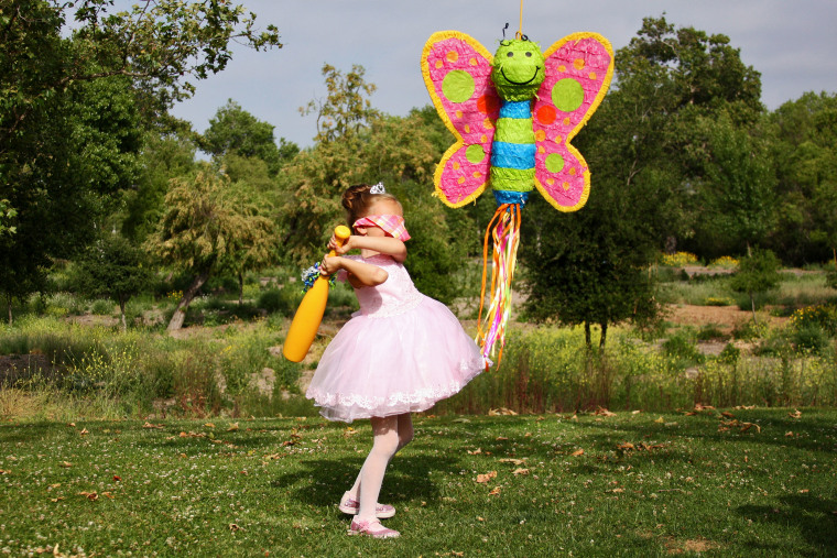 Birthday princess girl swings at butterfly piñata