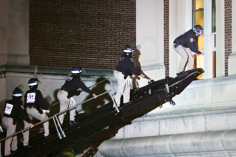 NYPD officers in riot gear break into a building at Columbia University.