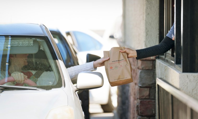 An employee hands a bag to a customer at the drive-thru of a McDonald's restaurant in Los Angeles on April 1, 2024.