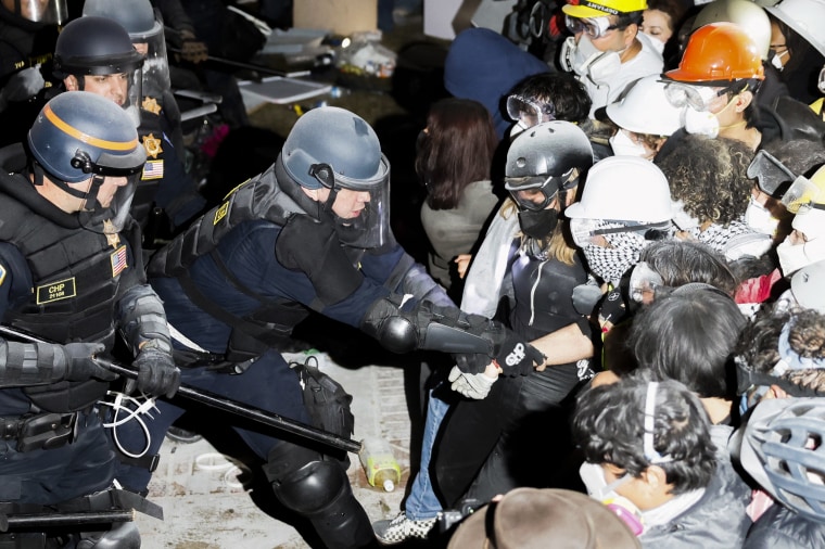 Police arrest protesters with their face covered.