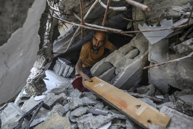 A Palestinian man searches inside a destroyed home
